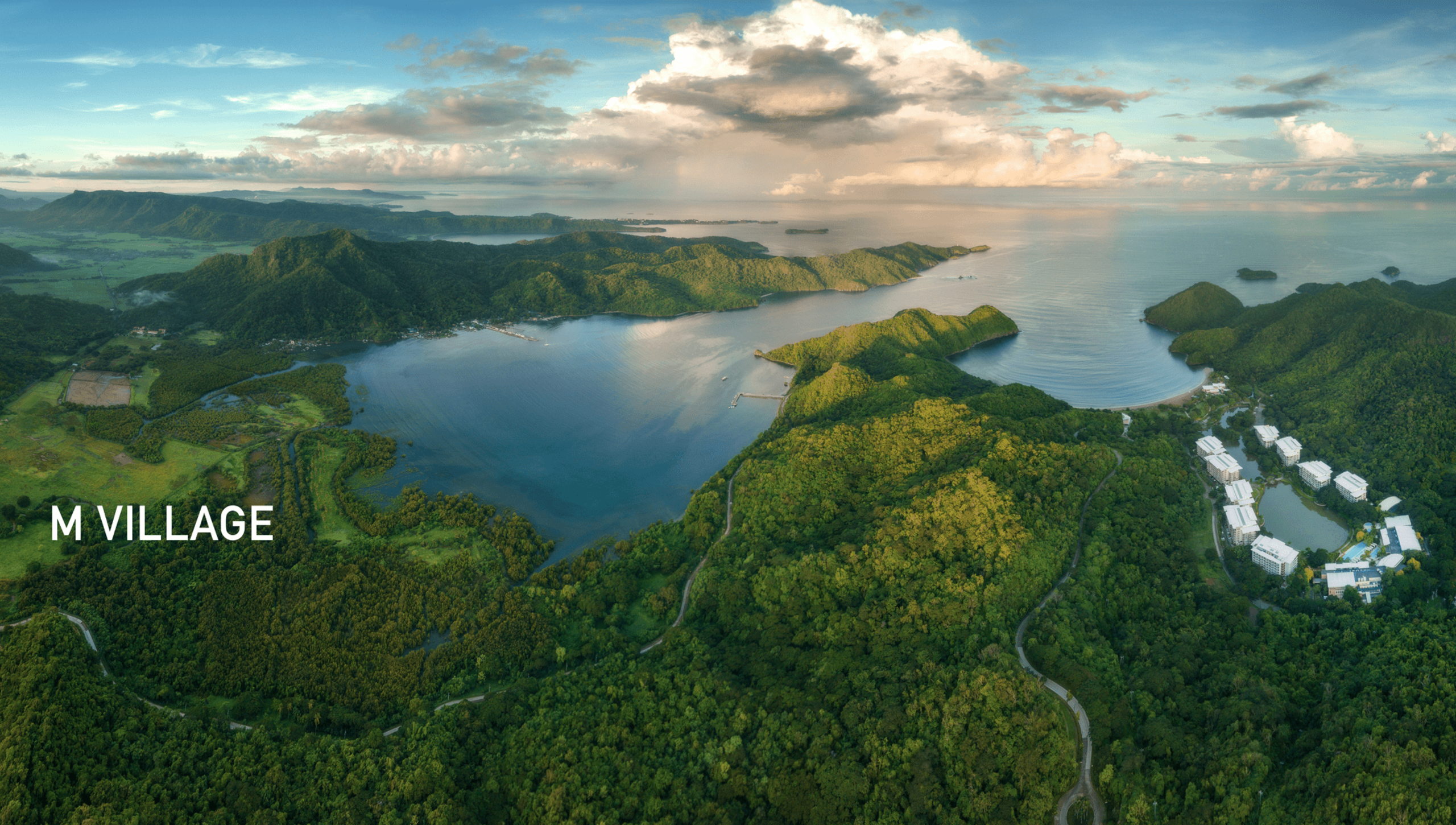 Aerial drone view of Pico De Loro Cove, showcasing its pristine beachfront, lush green mountains, and crystal-clear waters, offering a serene coastal retreat in Hamilo Coast.